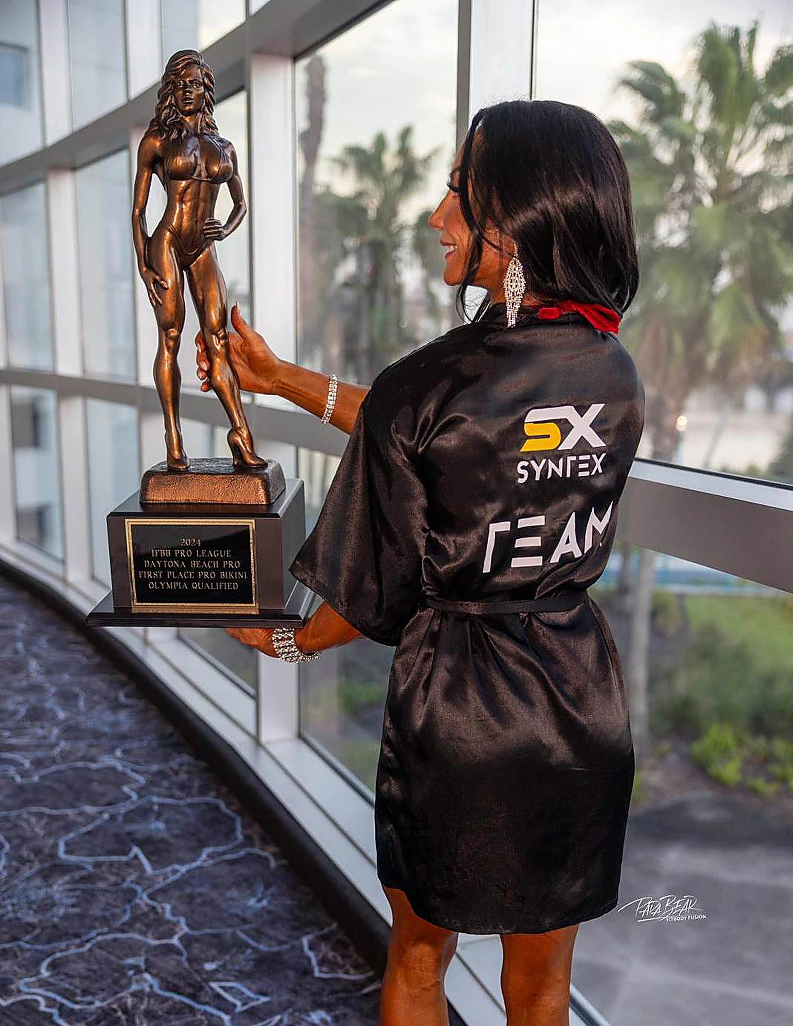 Atleta de Syntex Nutrition con trofeo y bata de laboratorio